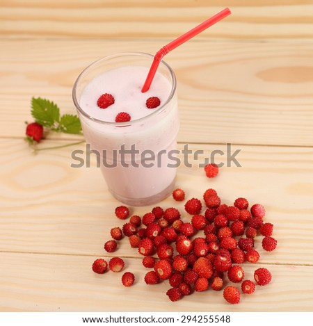 Smoothie from wild  strawberries in a glass and wild  strawberries on wooden table.