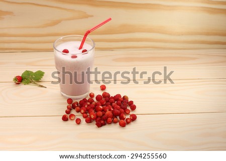 Smoothie from wild  strawberries in a glass and wild  strawberries on wooden table.