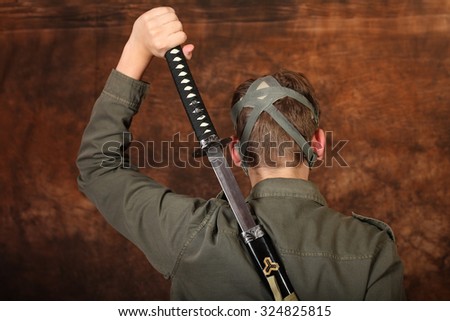 Man with gas mask and  katana sword on brown batik background