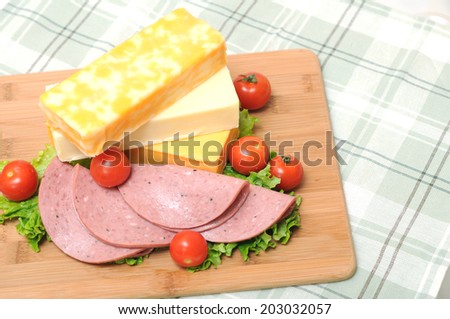 cheese bars, ham, tomato and salad on cutting board