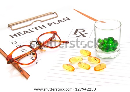 Glasses and pill capsules resting on health plan notes or patient record form