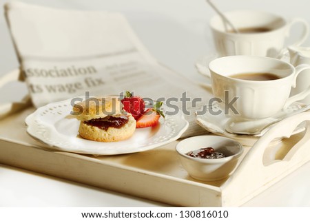 Scone with strawberry jam and clotted cream , afternoon tea break , cream tea , tea party , buttermilk biscuits with newspaper on table