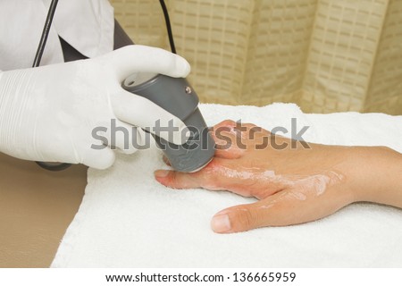 Physiotherapist is applying ultrasound therapy on the hand with ultrasound head transducer. Medical equipment use for release pain