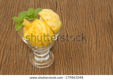 Pineapple slice in the glass with mint on wooden background