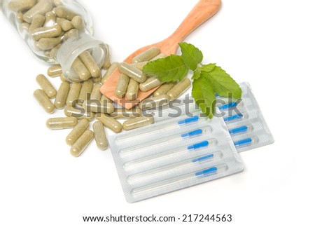 Herbal drug capsules in wooden spoon with Acupuncture needles ,Alternative medicine concept.