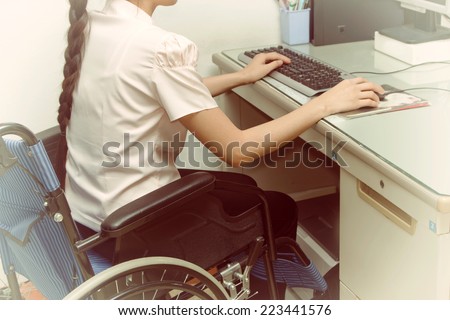Asia woman in wheelchair working on computer in the office