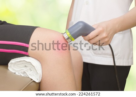 Physical therapist using ultrasound probe on woman patient \'s knee for release pain