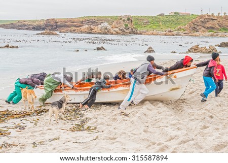 DOORNBAAI, SOUTH AFRICA - AUGUST 12, 2015: Fishermen move their boat to above the high water mark at Doornbaay (Thorn Bay). Sales from their daily catch is the only income for many families