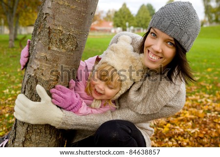 Mother having fun with her daughter in park in autumn