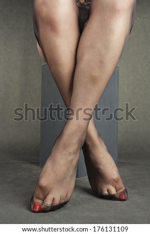 Woman legs wearing black hold-ups over grey background