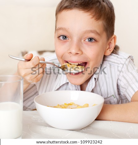 Child eat breakfast. Boy eating cereals with milk