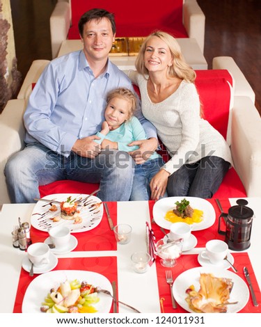 Happy family eating in restaurant. Mother, Father and child in cafe