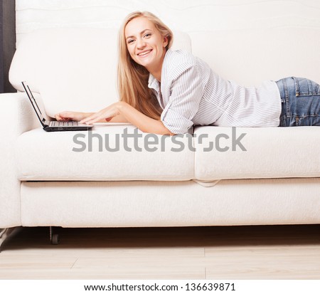 Woman on the sofa with laptop. Happy female with computer at hame
