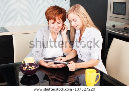 Mother and daughter looking in tablet pc. Two women with tablet computer. Family at home