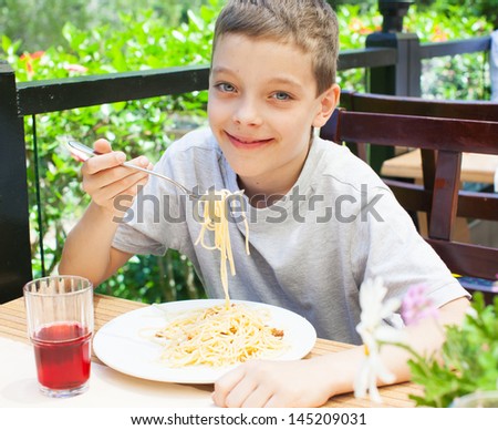 Child eating pasta in cafe. Boy eating spaghetti. Food