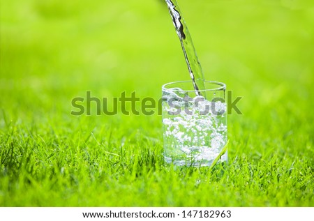 Water poured into glass. Pure water on green background