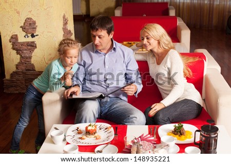 Family chooses the menu in the cafe. Mother, Father and child in cafe