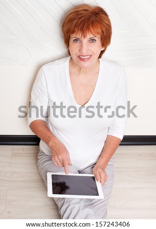 Mid woman with tablet computer. Mature female with digital tablet at home