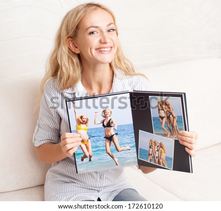 Young woman showing photo book. Female with photography album