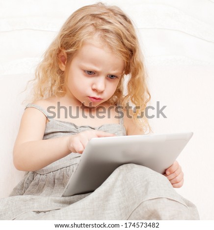 Concentrated child with tablet computer. Girl with pc at home