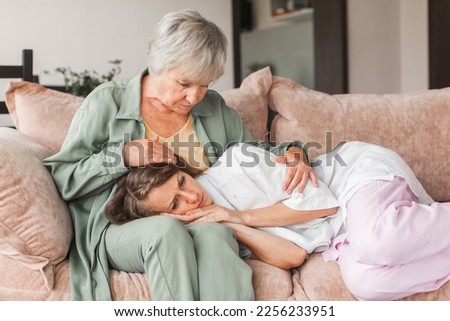 Worried aged mother embracing comforting grown up daughter with broken heart family sit on sofa, elderly mom soothe crying adult child, divorce or miscarriage, share problem with someone close concept Foto stock © 