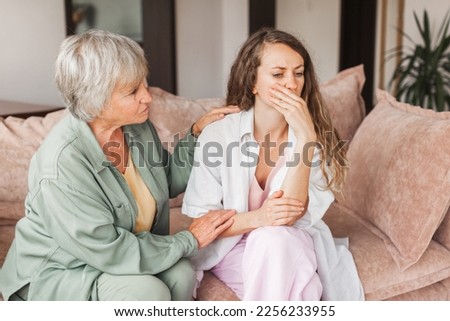 Worried aged mother embracing comforting grown up daughter with broken heart family sit on sofa, elderly mom soothe crying adult child, divorce or miscarriage, share problem with someone close concept Foto stock © 
