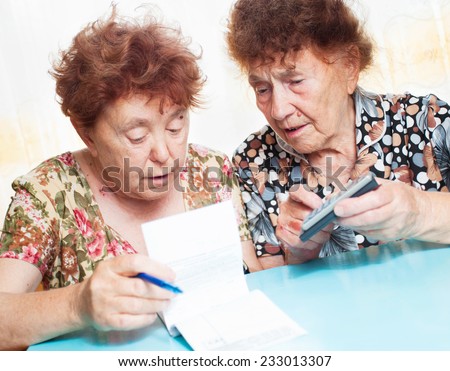Two old women consider receipts. Female counts bill