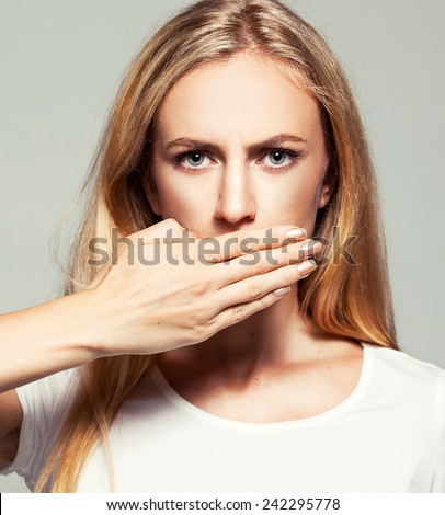 Woman with closed mouth. Female covers her mouth with her hands. Silence, fear, violence.