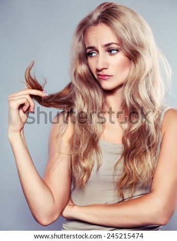 Young woman looking at split ends. Damaged long hair