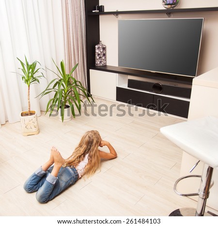 Child laying on the floor and watching TV at home