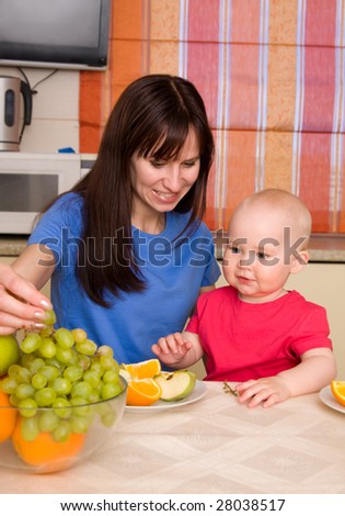 Beautiful happy mum with little son eat fruit