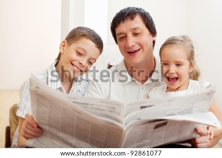 Happy family reading a newspaper. Father with daughter and son