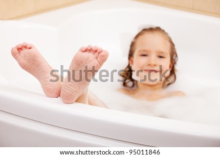 Child in the bathtub. Girl washes in the bathroom. Focus on foot