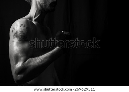 Close up to muscular arm, low contrast vignette black and white in studio