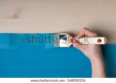woman hand painter paints the wooden table