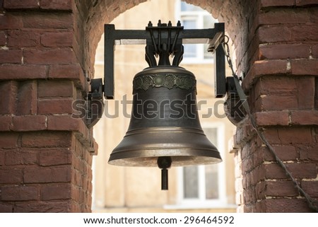 The old bronze bell near the brick wall