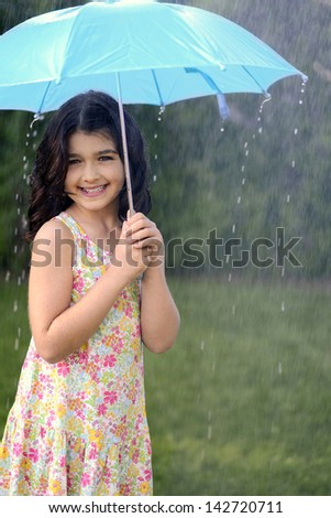 young girl playing in rain with umbrella