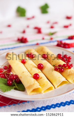 Pancakes rolled into a tube and decorated with red currant berries.