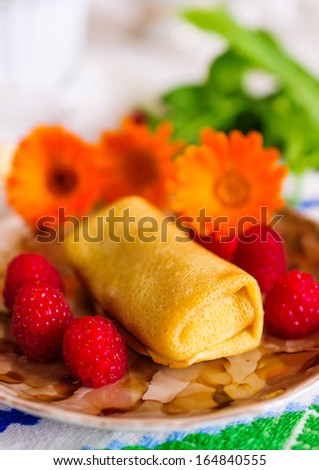 Pancakes with filling. Decorated with raspberry and orange flowers.