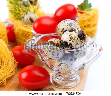 Glass Gravy boat with quail eggs. On the background of pasta nests and cherry tomatoes.