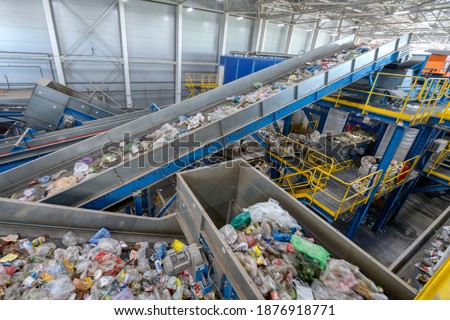 Waste sorting plant conveyors filled with various household waste. Modern waste processing.