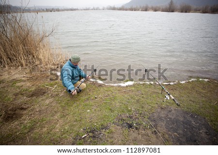 Angler setting his rods for a big carp. Windy weather in a spring time.