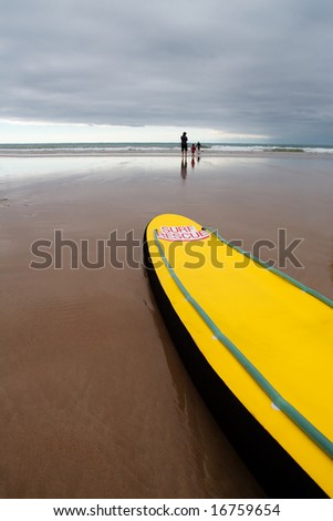 Surf rescue board on the beach, storm approaching in the background.
