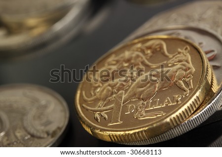 Various australian coins, focus on gold 1 dollar coin.