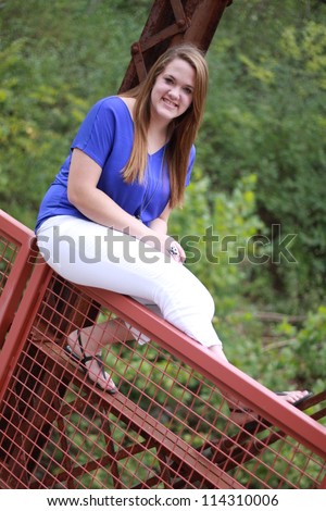 Young woman sitting on the edge of an old rusted bridge in Columbia, Missouri.