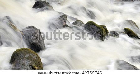 Forest waterfall in spring, strong streams of water fight about stones