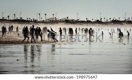 Silhouettes of various people playing football, walking and running at the beach covered with fog, Casablanca Beach, Morocco, Africa
