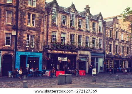 EDINBURGH, SCOTLAND - SEPTEMBER 16, 2014: Row of pubs at Grassmarket in an old town. Former place of public execution. People sitting and drinking outside