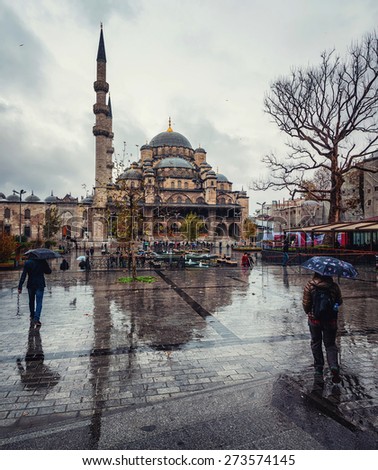 Rainy day in Istanbul, Turkey. People with umbrellas in front of New Mosque