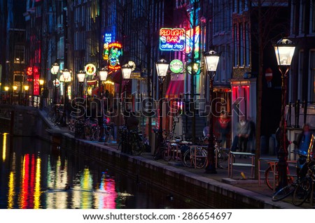 AMSTERDAM, NETHERLANDS - MARCH 16, 2014: Night view of Red - light district, where is a concentration of sex shops, strip clubs, adult theaters, etc. The sign of Red Light Bar coffee shop